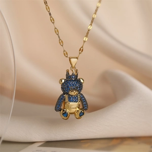 Macro shot of gold teddy bear pendant with blue crystal inlay on silk fabric