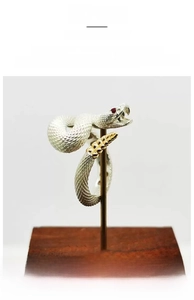 Detail of rattlesnake ring with silver scales, golden tail tip, and red zircon eyes