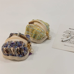 Close-up of plaid tweed earphone cases with elegant pearl zippers in blue and green