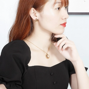 Set di gioielli dorati con collana a ciondolo luna e stella e orecchini a lobo su modella