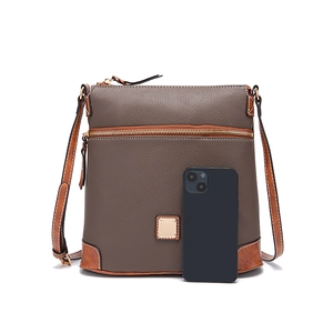 Close-up of pebble leather texture and metal logo plate on a taupe crossbody bag