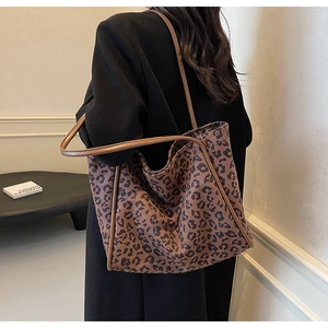 Close-up of leopard print tote bag with long shoulder straps worn by a fashion model