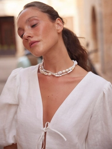 Detail of layered white baroque pearl necklace with gold accents on female model