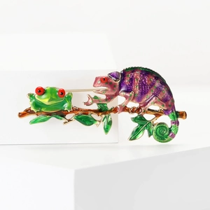Detail of colorful enamel chameleon and frog on a golden branch with red eyes