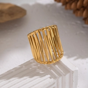 Detail of a wide hollow gold ring on a white textured stone base with natural lighting