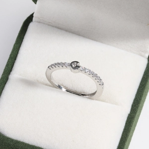 Macro shot of silver letter G ring with clear crystals on green velvet jewelry box