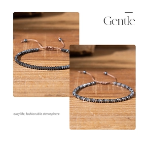 Close-up of hematite bead bracelet with adjustable brown cord on a wooden surface