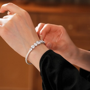 Détail d'un bracelet en argent avec zircons en cœur au poignet, finition polie