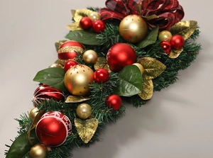 Detail of Christmas teardrop swag with green pine needles, red ornaments and checkered bow