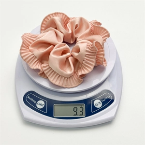 Pink satin ruffle scrunchie for women weighing 9.3g on a white scale display