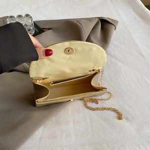 Elegant gold metal satin evening bag with chain strap shown in an open position