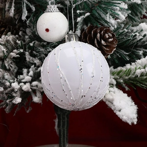 Close-up of white and silver glitter Christmas balls hanging on snow-covered pine branches