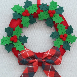 Detailed view of Christmas wreath with holly leaves and red black plaid bow hanging decoration