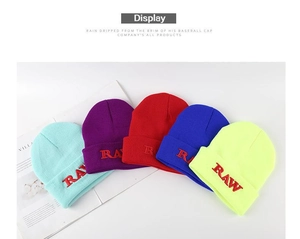 Detail showing colorful knit beanies with red RAW embroidery on the folded cuff