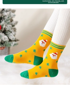 Dettaglio di calze natalizie gialle con Babbo Natale su un tappeto di peluche bianco