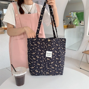 Black quilted floral tote bag with yellow small flower pattern and shoulder strap