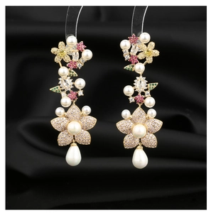Macro shot of long drop earrings with floral zircon patterns and hanging pearl accents