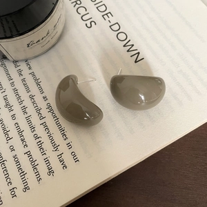 Macro view of geometric C-shaped taupe resin stud earrings on a vintage book