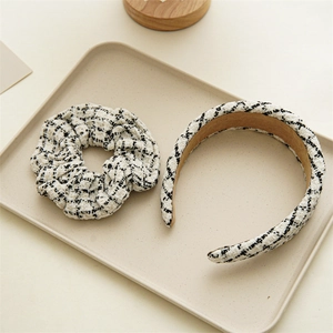Macro view of black and white tweed scrunchie and headband set on a neutral display tray