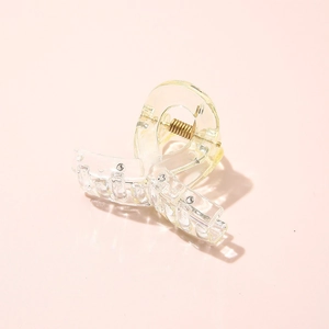 Macro shot of a small transparent hair claw clip with a durable metal spring detail