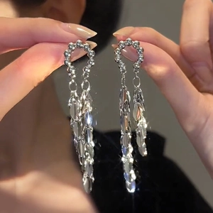 Detailed macro view of long silver tassel earrings with tiered metal leaf pendants