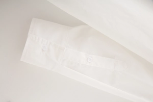 Close-up of white cotton poplin shirt cuff with fine stitching and button detail