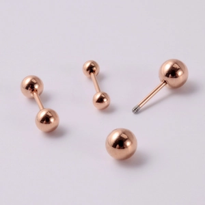 Gros plan sur les boucles d'oreilles barre en acier inoxydable or rose et billes polies