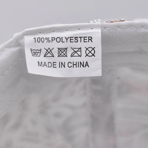 Detail of white baseball cap inner wash label showing 100% polyester and care instructions