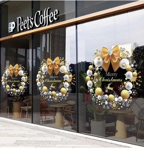 Detailed Christmas wreath window stickers with gold bows and ornaments on a glass storefront