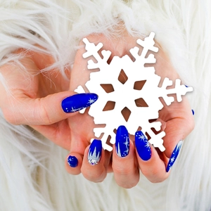 Blue Christmas nails with snowflake art and gems on white faux fur background