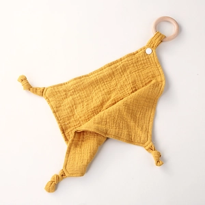 Detail of yellow cotton muslin baby comforter with natural wooden teething ring and snaps