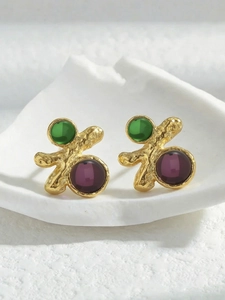 Détail des boucles d'oreilles irrégulières en or avec pierres vertes et violettes