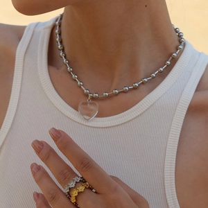 Minimalist beaded chain necklace with transparent heart pendant and floral rings on model