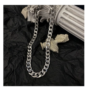 Vue détaillée du collier à mailles cubaines argentées sur piédestal et sculpture