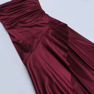 Detail of burgundy satin dress showing elegant draped pleats and a high side slit design