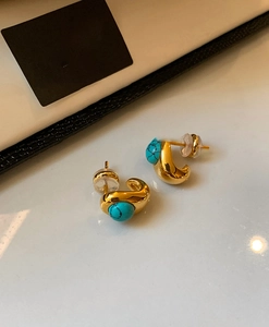 Close-up of 18k gold plated stud earrings featuring turquoise stones and silicone backs