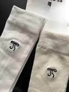 Close-up of black bow embroidery on breathable white knit cotton calf socks