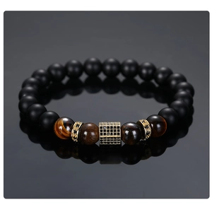Close-up of matte black beads and tiger eye stones with a gold micro-pave hexagon charm