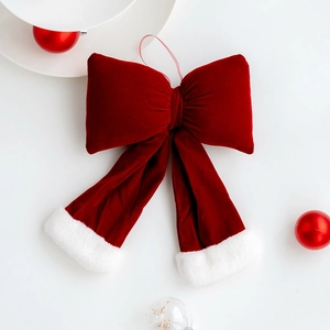 Large red velvet Christmas bow with white fur trim hanging on a white background