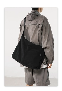 Large black nylon crossbody bag shown on a model for casual streetwear style