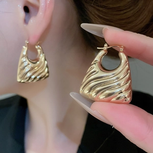 Detailed view of gold earrings with ripple texture and secure lever-back closure