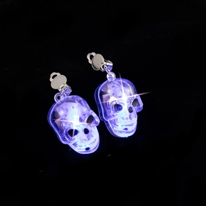 Close-up of glowing purple LED skull earrings with transparent plastic and metal clips