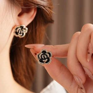 Close-up of model wearing black and gold camellia earrings with sparkling crystals