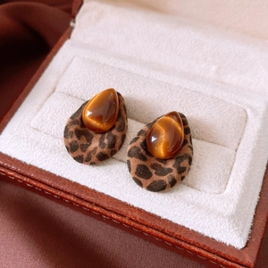 Macro detail of leopard print resin earrings with amber stone in a velvet box