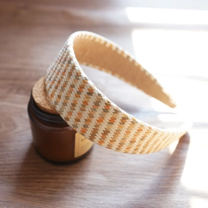 Detailed close-up of woven raffia headband showing multi-colored beige and orange textures