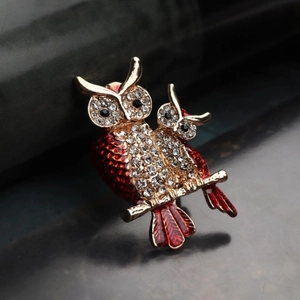 Sparkling red owl brooch with crystals and gold finish on dark background