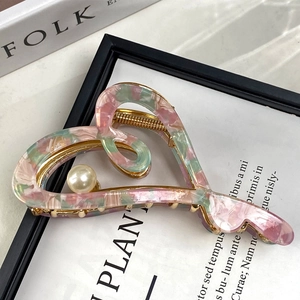 Vue détaillée de la pince à cheveux cœur en acétate marbré rose et vert avec perle