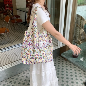 Grande borsa shopper in tela gialla con fantasia floreale colorata in un set all'aperto