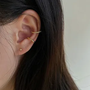 Gros plan de boucles d'oreilles dorées en forme de C et clous en style superposé