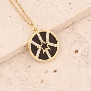 Macro detail of gold star pendant with micro-paved zircons on black inlay disk